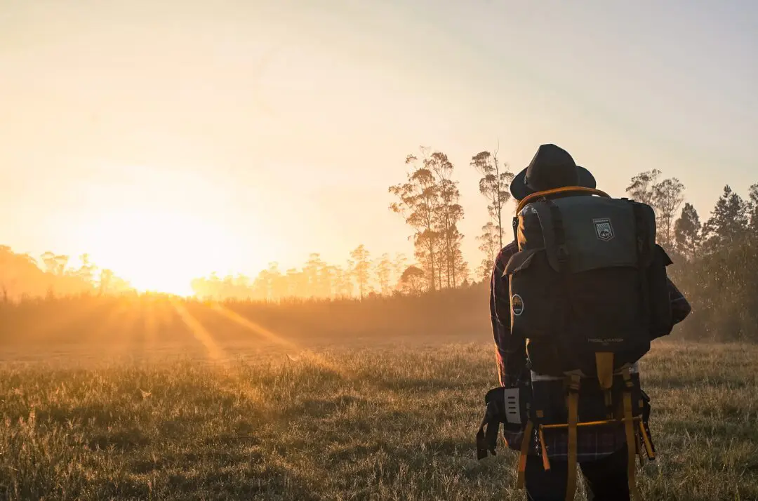 A person with a backpack and camera in the field