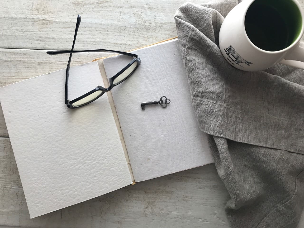 A pair of glasses and a key on top of an open notebook.