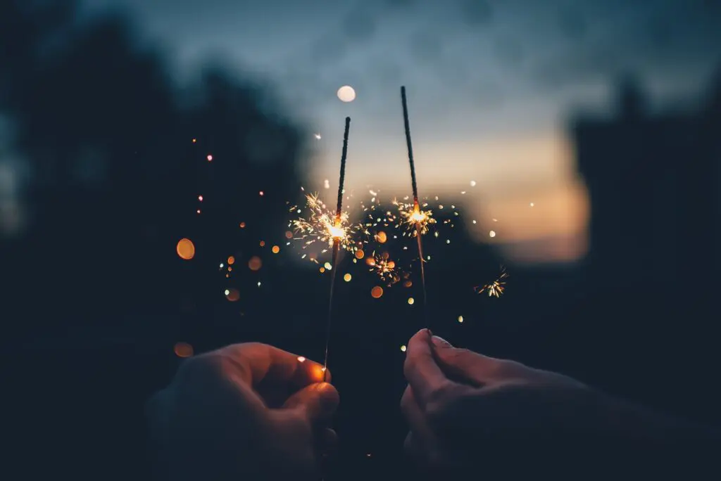 A person holding sparklers in their hands.