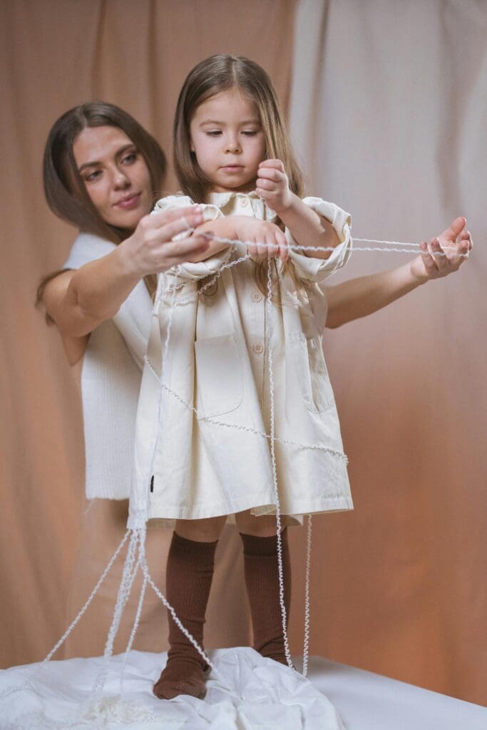 A woman and child are playing with string.