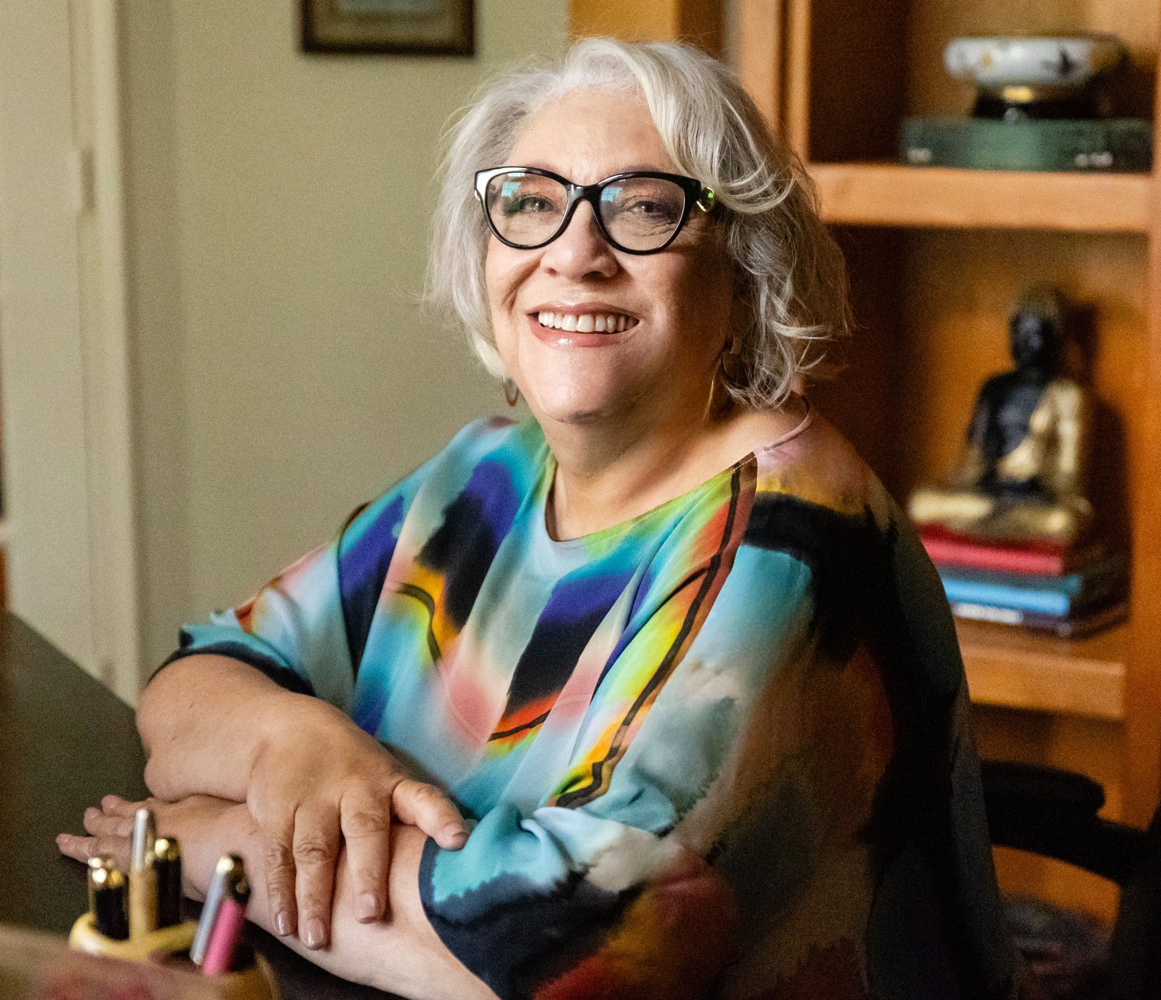 A woman sitting at a table with her arms crossed.