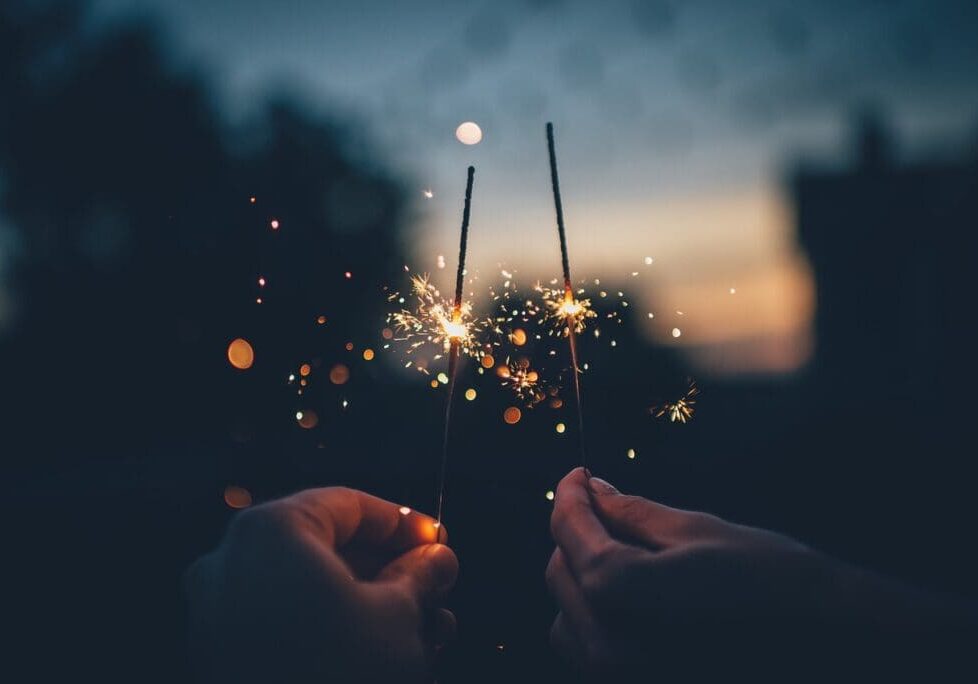 A person holding sparklers in their hands.